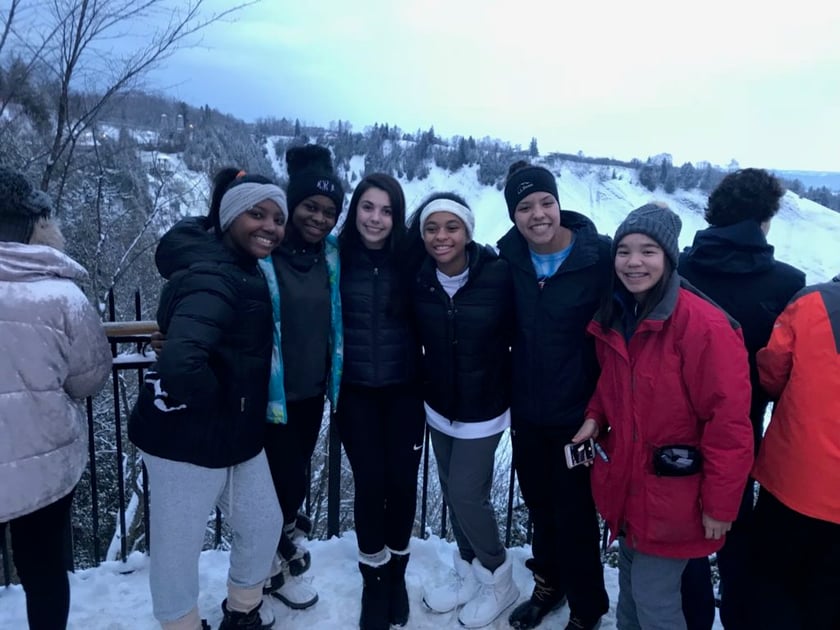 Six teenager girls are smiling at the camera during their educational tour in Quebec in a snowy background