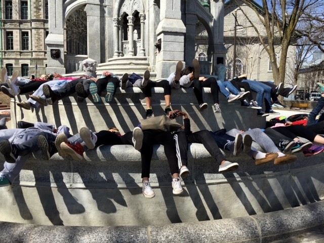Students are lying in a dry fountain during a student trip and we can only see their feet